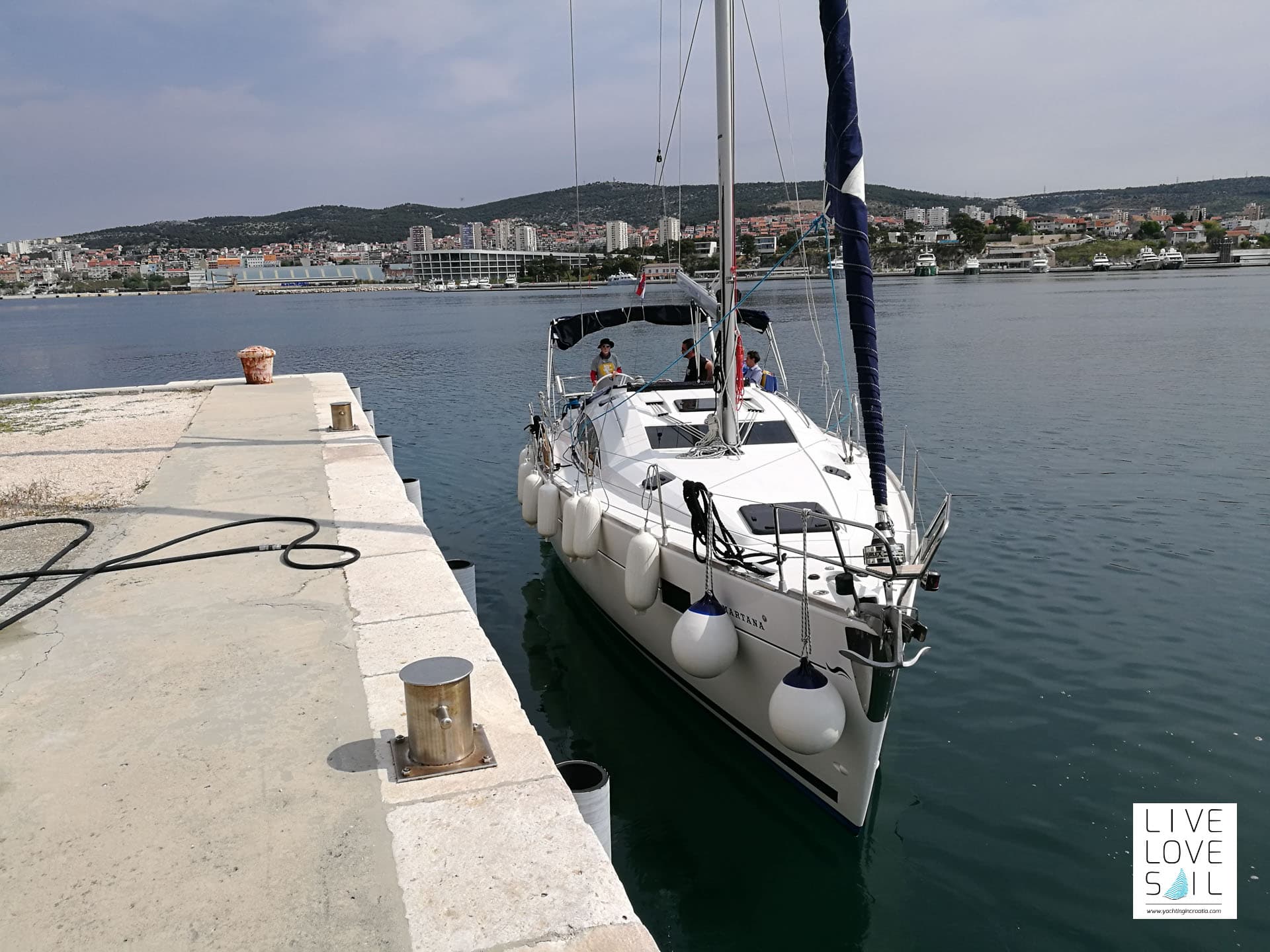 Single boat docking at a marina with hills and town in the distance